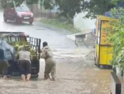 Bripka Galih Kunto Bhabinkamtibmas Jatimurni Bantu Dorong Mobil Mogok Akibat Buruknya Drainase.